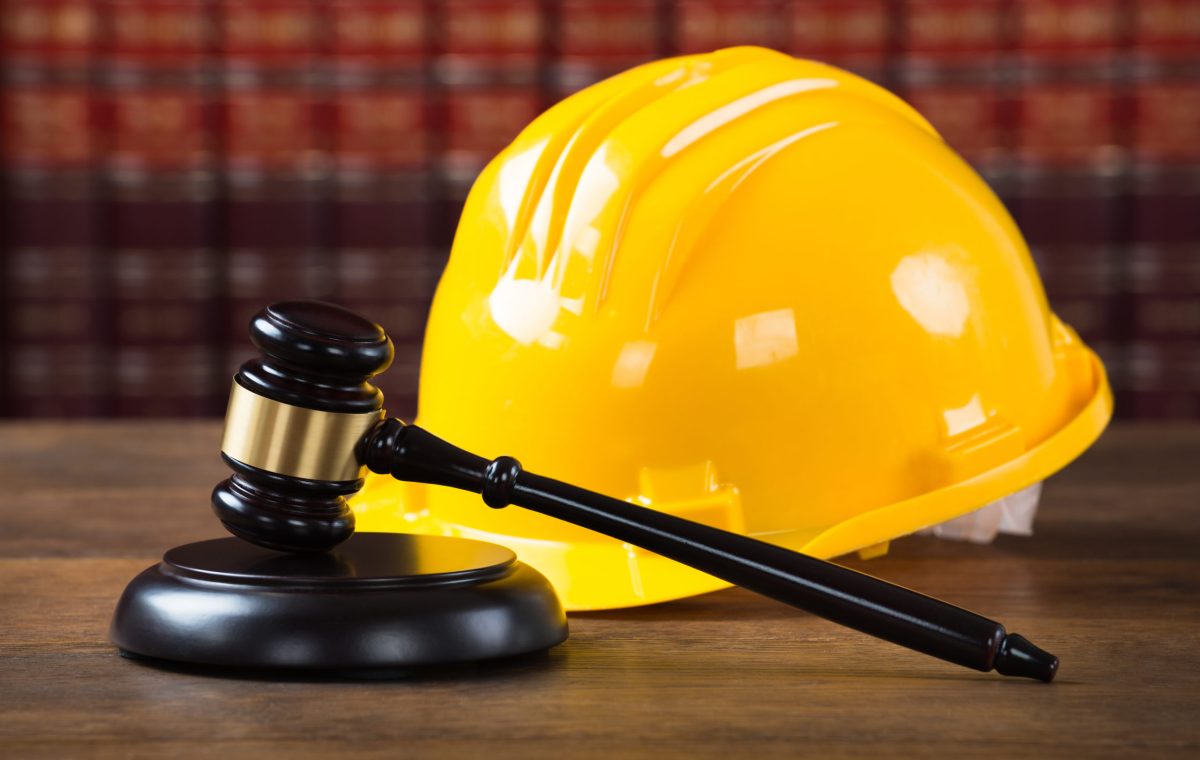 Closeup of wooden mallet and yellow hardhat on table in courtroom